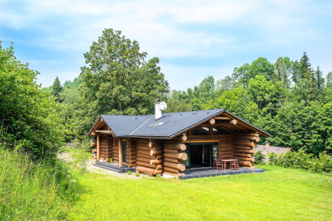 Chalet di tronchi Lomnice nad Popelkou LLB005 immerso nel verde, circondato da alberi e cielo sereno.
