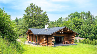 Houten chalet Lomnice nad Popelkou LLB005 omringd door gras en bomen onder een heldere blauwe hemel.