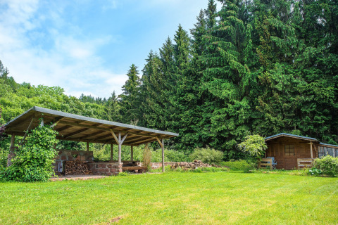 Zona relax coperta e casetta di legno accanto a un bosco e prato verde, presso uno chalet in Repubblica Ceca.