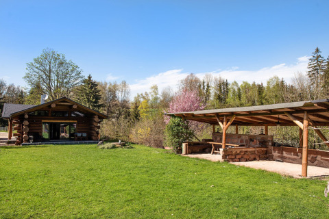 Chalet in legno e terrazza coperta immersi nel verde a Lomnice nad Popelkou, Repubblica Ceca, cielo sereno.