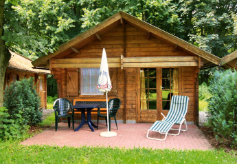 Eine 30 m² große Blockhütte in Deutschland mit Terrasse, Gartenmöbeln und Liegestuhl im Grünen.