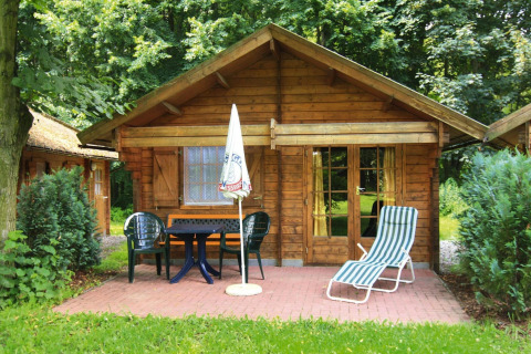 Een 30 m² blokhut in Duitsland met terras, tuinmeubels en een ligstoel tussen het groen.