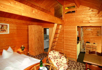 Cozy 30 m² log cabin in Germany featuring wooden interior, bed, small kitchen, and seating area.