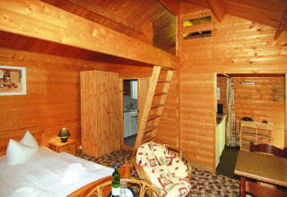 Gezellige blokhut van 30 m² in Duitsland met houten interieur, bed, keukentje en zithoek.
