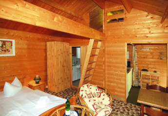 Acogedora cabaña de troncos de 30 m² en Alemania con interior de madera, cama y pequeña cocina equipada.