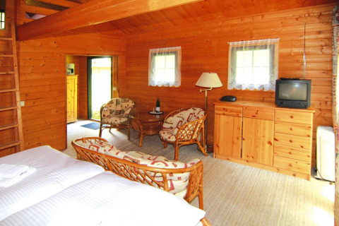 Interior de una acogedora cabaña de troncos en Alemania con paredes de madera, muebles rústicos y ventanas.