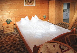 Gezellig interieur van een blokhut van 30 m² in Duitsland met dubbel bed en houten meubelen.