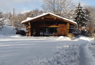 Chalet in legno immerso nella neve a Lomnice nad Popelkou LLB005, Repubblica Ceca, circondato da alberi.