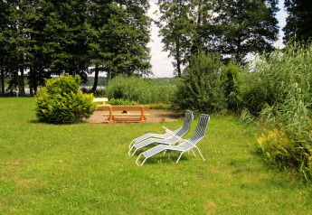 Espace extérieur près d’un chalet en Allemagne avec deux transats, un banc et une végétation verdoyante.