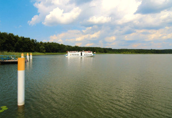 View of a lake with a boat in the distance near Log cabin «30 m²» in Germany, surrounded by nature.