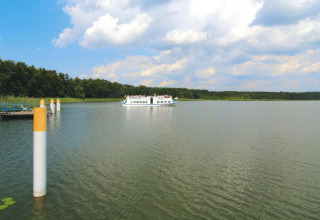 Vista de un lago con un barco a lo lejos cerca de la Log cabin «30 m²» en Alemania, rodeado de naturaleza.