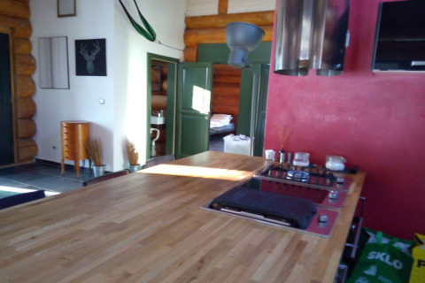 Cucina e soggiorno di chalet con tavolo in legno, parete rossa e porte verdi a Lomnice nad Popelkou, Repubblica Ceca.