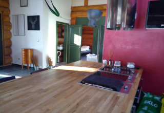 Cucina e soggiorno di chalet con tavolo in legno, parete rossa e porte verdi a Lomnice nad Popelkou, Repubblica Ceca.