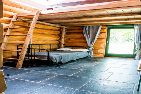 Interno dello chalet Lomnice nad Popelkou LLB005 in Repubblica Ceca con pareti di tronchi, letto e scala.