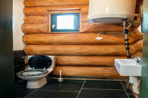 Bagno in chalet a Lomnice nad Popelkou, Repubblica Ceca, con pareti in legno, WC e lavandino.