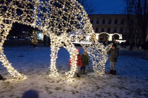 Bambini accanto a una scultura luminosa di animale sulla neve a Lomnice nad Popelkou, Repubblica Ceca, di sera.