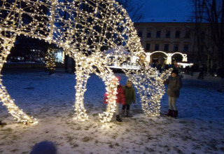 Bambini accanto a una scultura luminosa di animale sulla neve a Lomnice nad Popelkou, Repubblica Ceca, di sera.