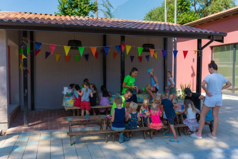 Children enjoy a group craft activity under colorful bunting at Trasimeno Glamping Resort in Umbria, Italy.