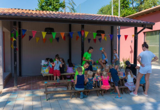 Bambini partecipano a un'attività creativa sotto festoni colorati al Trasimeno Glamping Resort in Umbria.