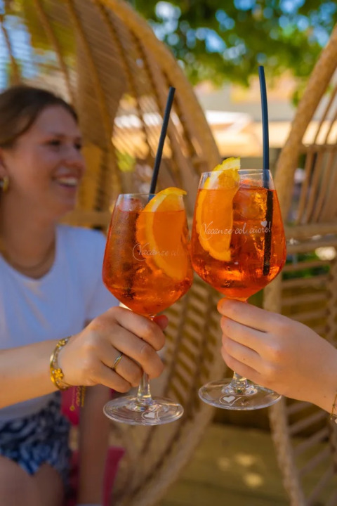 Due persone brindano con Aperol Spritz in bicchieri al Trasimeno Glamping Resort in Umbria, Italia.