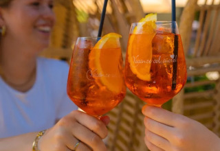 Two people toast with Aperol Spritz in glasses at Trasimeno Glamping Resort in Umbria, Italy.