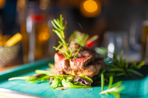Bistecca succulenta con erbe aromatiche servita su piatto verde al Trasimeno Glamping Resort in Umbria.