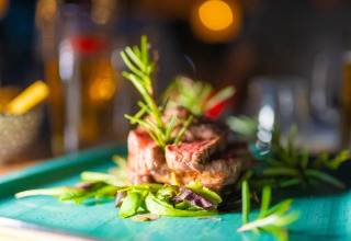 Bistecca succulenta con erbe aromatiche servita su piatto verde al Trasimeno Glamping Resort in Umbria.