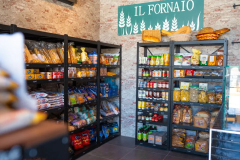 Scaffali con alimentari italiani e pane sotto l'insegna 'IL FORNAIO' al Trasimeno Glamping Resort.