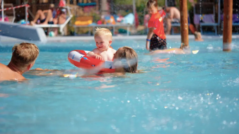 Bambini e adulti si divertono in piscina al Trasimeno Glamping Resort, villaggio turistico in Umbria, Italia.