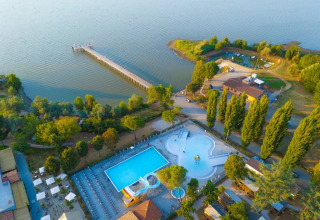 Vista aerea del Trasimeno Glamping Resort in Umbria, Italia, con piscina, alberi e lago con pontile.