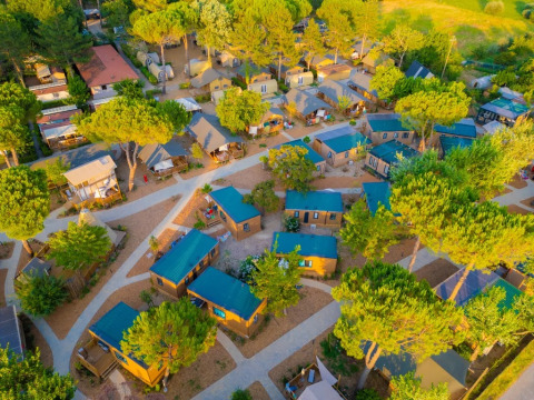 Aerial view of Trasimeno Glamping Resort in Umbria, Italy, showing cabins and tents nestled among trees.