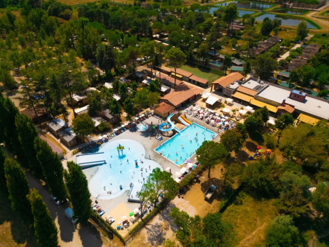 Aerial view of Trasimeno Glamping Resort in Umbria, Italy, featuring pools, slides, sun loungers and trees.