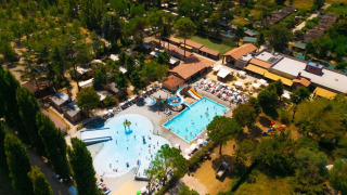 Luchtfoto van Trasimeno Glamping Resort in Umbrië, Italië, met zwembaden, glijbanen en omringd door bomen.