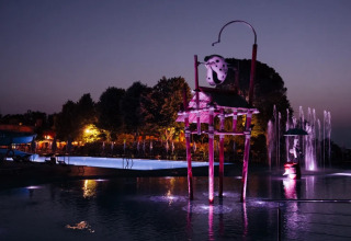 Piscina illuminata con figure fantasiose al Trasimeno Glamping Resort in Umbria, Italia, al tramonto.