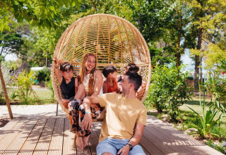 Famiglia felice si rilassa su un'altalena di vimini al Trasimeno Glamping Resort in Umbria, Italia.