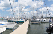 Gezicht op een drijvende steiger met veel aangemeerde zeilboten in Marina Parcs Lelystad, Flevoland.
