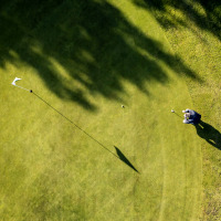 Luftaufnahme einer Person beim Golfspielen auf einem gepflegten Grün in einem Ferienpark.