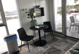 Kleine zithoek met twee stoelen en ronde tafel, decoratief met vaas en boeken, bij Marina Parcs Amsterdam.