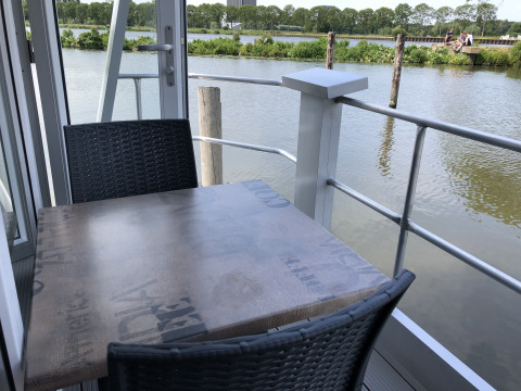 Een houten tafel met zwarte stoelen op een terras bij het water in Marina Parcs Amsterdam, Nederland.