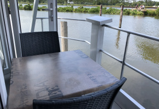Een houten tafel met zwarte stoelen op een terras bij het water in Marina Parcs Amsterdam, Nederland.