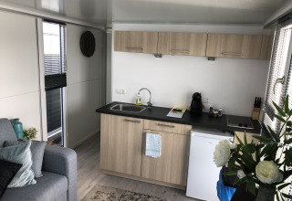 Moderne kitchenette in een vakantiewoning bij Marina Parcs Amsterdam met een bank, bloemen en licht interieur.