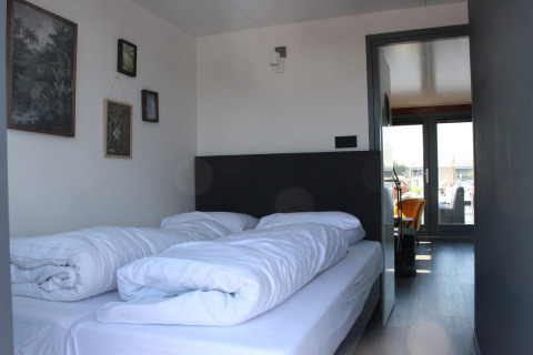 Een moderne slaapkamer met twee bedden en witte dekens in Marina Parcs Amsterdam, vakantiepark in Noord-Holland.