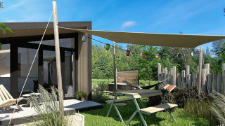 Zona exterior de la Tiny Wellness Cabin en Holiday Park De IJsvogel con toldo y muebles de jardín, Países Bajos.