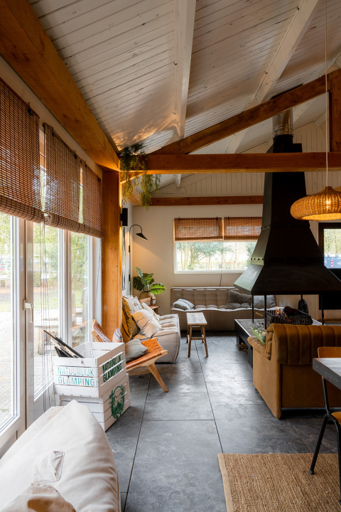 Gezellige woonkamer in Resort de Parel, Flevoland met houten balken, moderne haard en grote ramen.