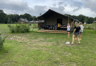 Vakantiegangers genieten van een spel buiten bij een safaritent op Camping de Heerlijkheid Vorenseinde.