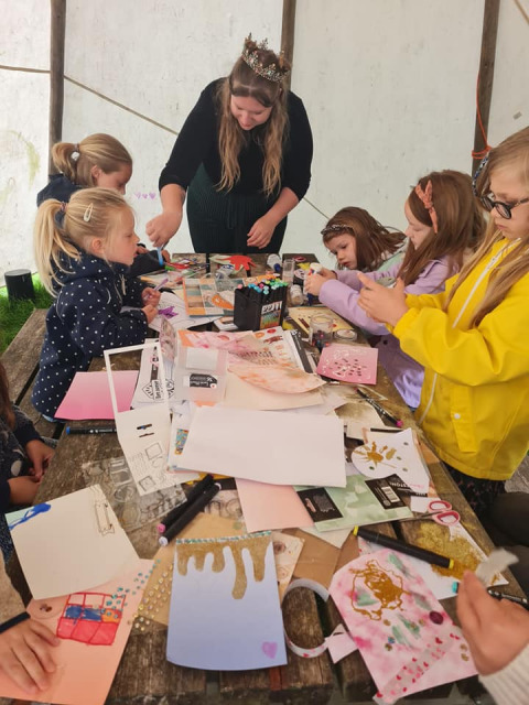 Niños haciendo manualidades en una mesa bajo una carpa en Camping Emmen, un parque vacacional en Drenthe.