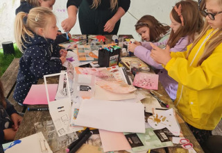 Children creating colorful crafts at a table during an activity at Camping Emmen holiday park in Drenthe.