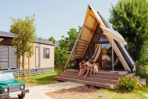 Gezin zit ontspannen voor de safari-tent ‘A Luxury’ bij Trasimeno Glamping Resort in Italië.
