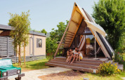 Famiglia rilassata davanti alla tenda safari 'A Luxury' al Trasimeno Glamping Resort in Italia in una giornata di sole.