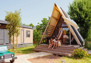 Gezin zit ontspannen voor de safari-tent ‘A Luxury’ bij Trasimeno Glamping Resort in Italië.